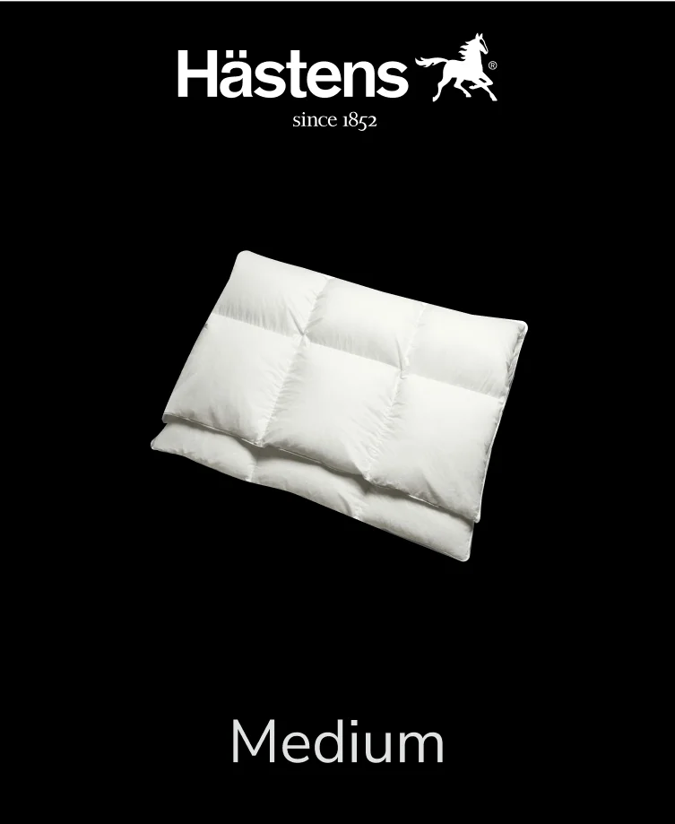 Fluffy white Hastens Medium down comforter on a simple wooden bed frame