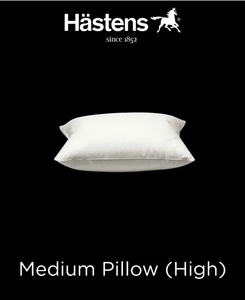 Fluffy white Hastens Medium High Pillow propped against a headboard