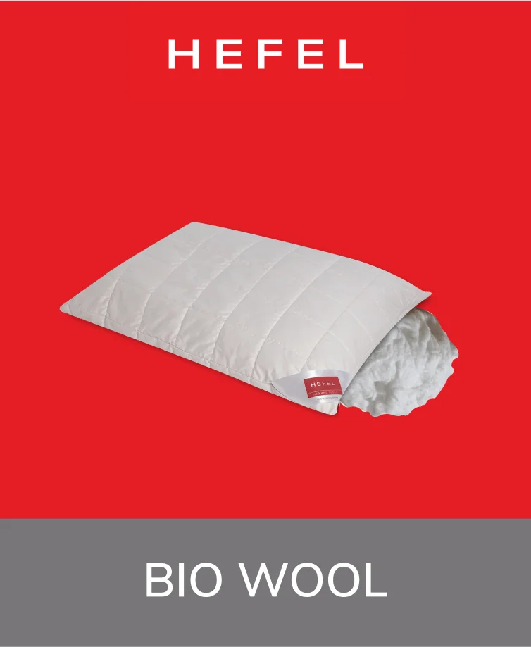 Hefal Bio-Wool Pillow in a natural cream color, displayed on a bed